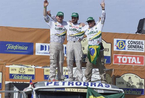 Da esq para a dir: Tomas Tomecek  Mira Martinec e André Azevedo comemoram resultado no pódio do Dakar 2003 (foto: Ricardo Ribeiro / VipComm)