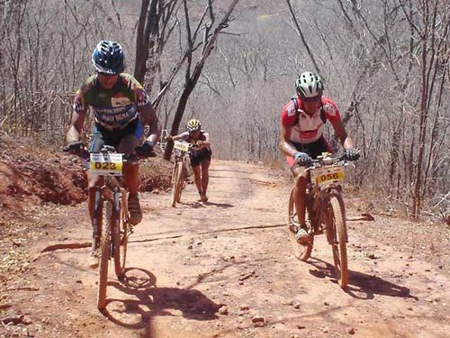 Atletas empurram bike na subida em meio à caatinga. (foto: Camila Christianini/ www.webventure.com.br)